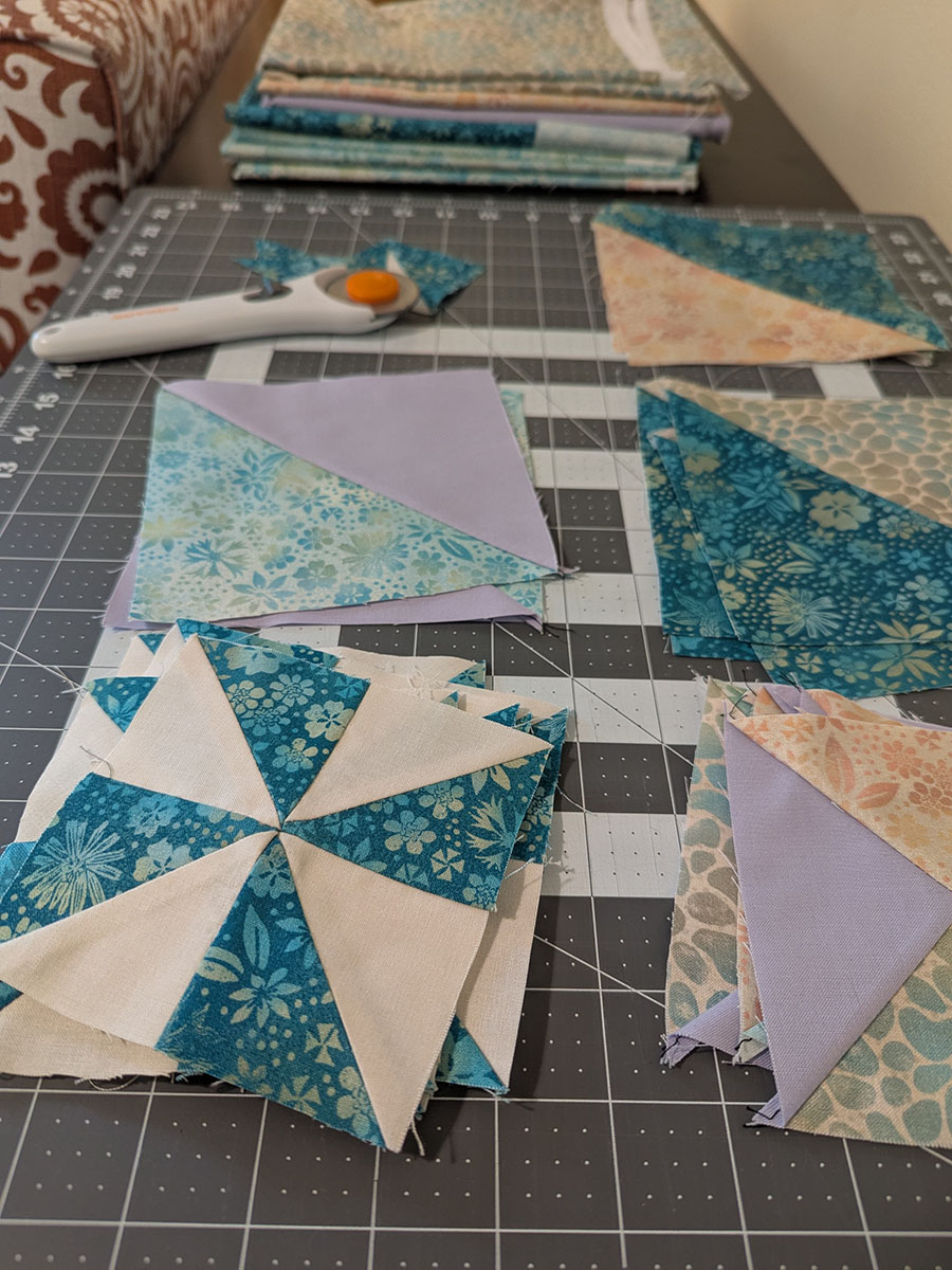Hand-pieced quilt blocks and a rotary cutter on a cutting mat